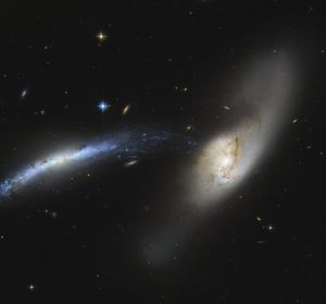 An interacting pair of galaxies. The one at the left of the image likes like a blue-white streak. The one at center-right is whitish with brown streaks. The blue one appears warped, and seems to be getting ripped apart. Rain comes to mind when looking at this, like the stars and gas of the blue galaxy are mere particles condensing and falling into the white galaxy like rain.